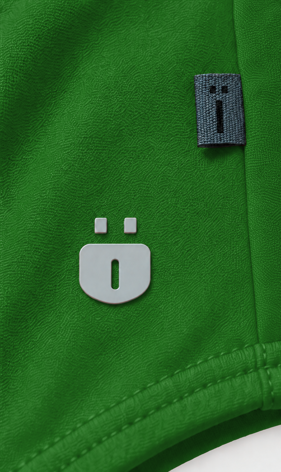 Close-up of a bright green athletic fabric with a small gray rectangular woven logo tab and a larger matching gray logo patch on the front.