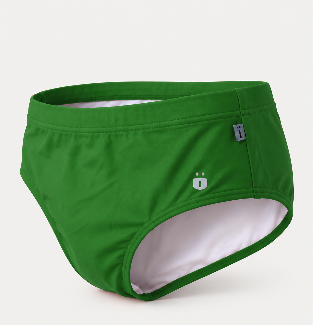 Green swim briefs with a white interior lining, featuring a small white logo and a gray brand tag on the side, set against a light gray background.